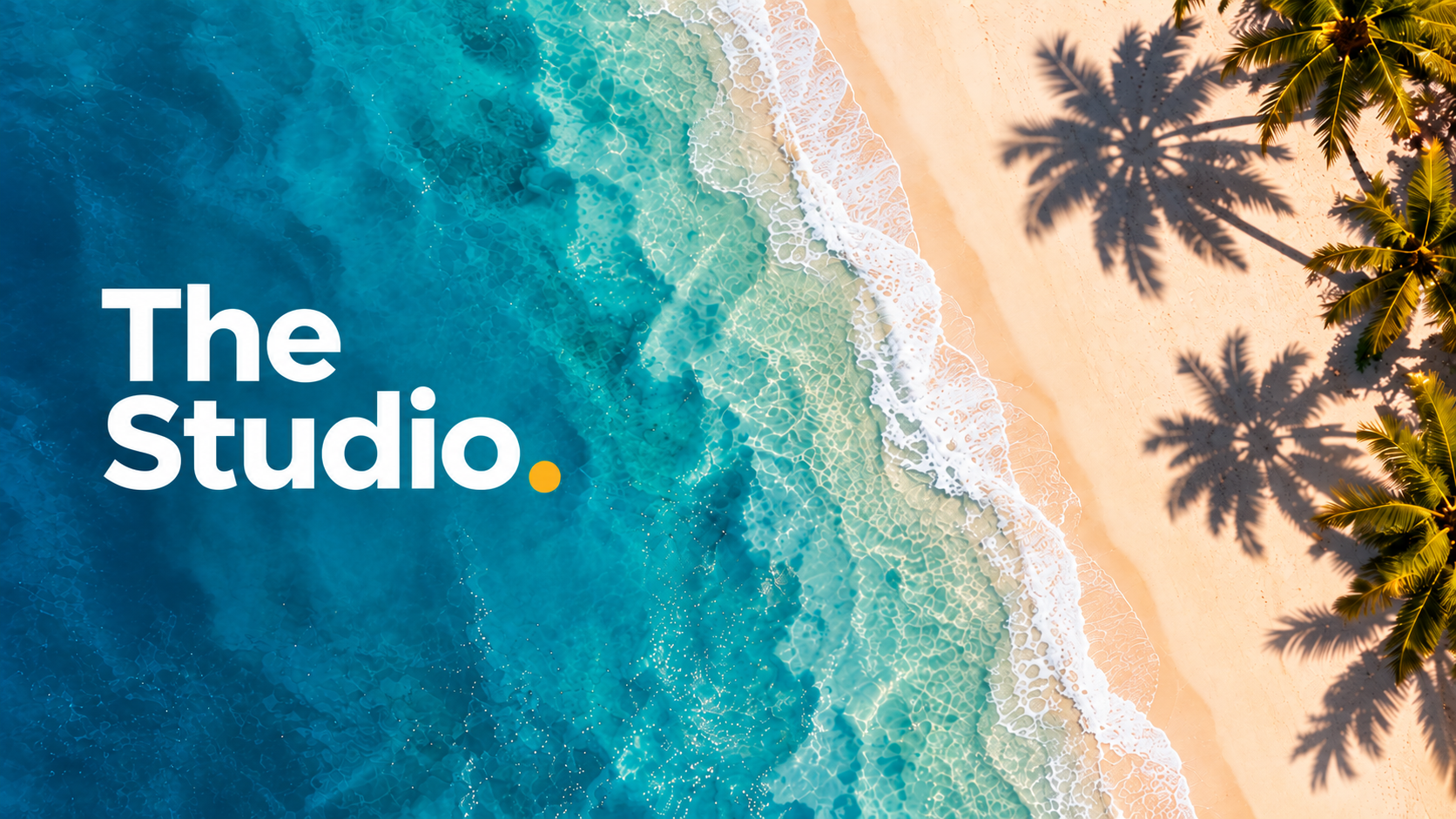 The Studio over an aerial view of clear turquoise water meeting a sunlit beach